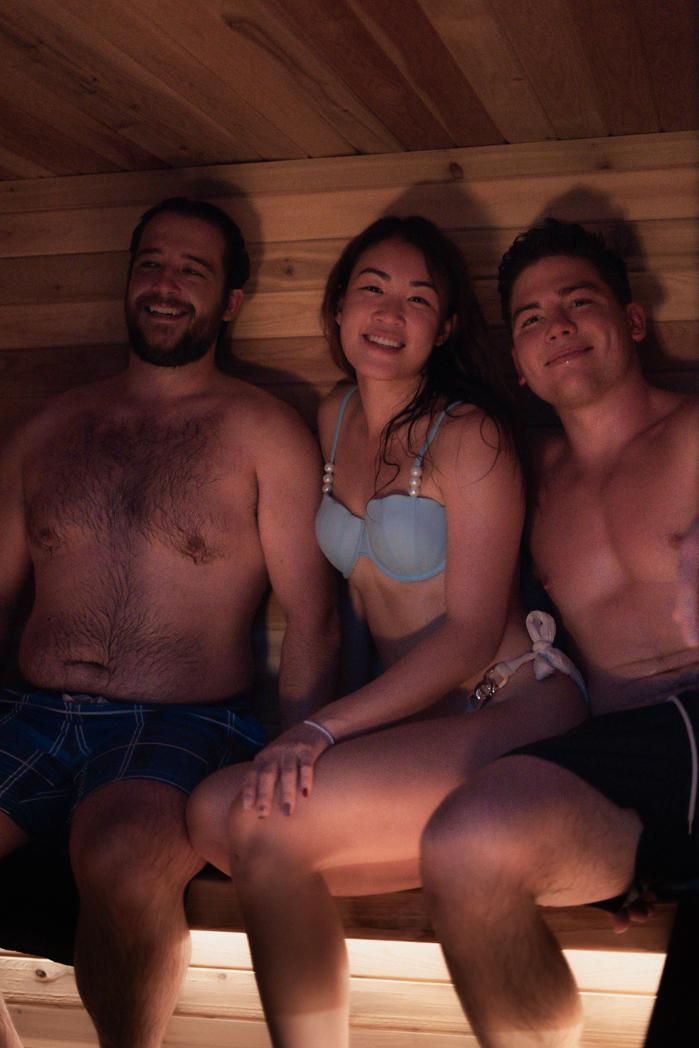 Three guests smiling together inside the cedar-lined Sweat Culture wood-fired sauna during a social session in Peachland, BC