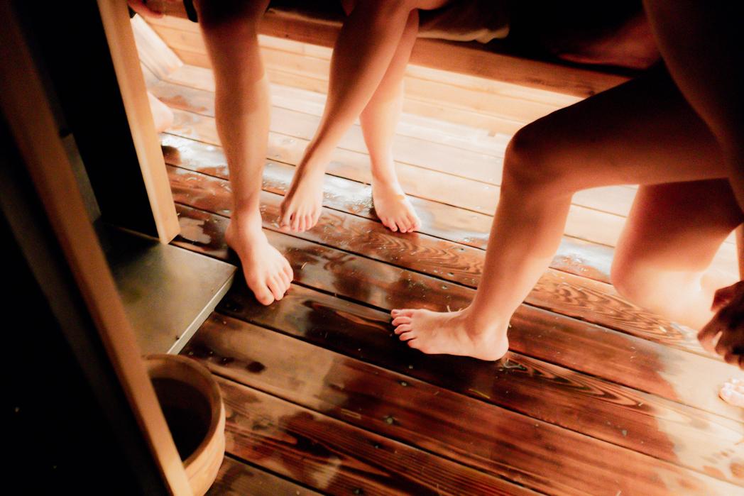 Bare feet on warm cedar sauna floor inside the Sweat Culture wood-fired trailer sauna, an intimate detail of a sauna session in Peachland, BC