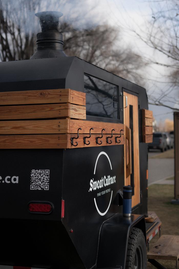 Close-up of the Sweat Culture trailer sauna with smoke rising from the chimney stack on a clear day in Peachland, BC