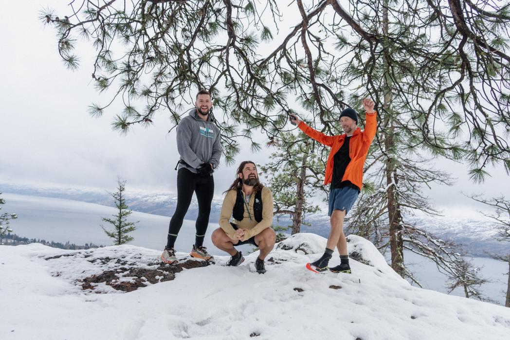 Three Sweat Culture run club members celebrating on a snow-covered summit above Okanagan Lake in Peachland, BC in December