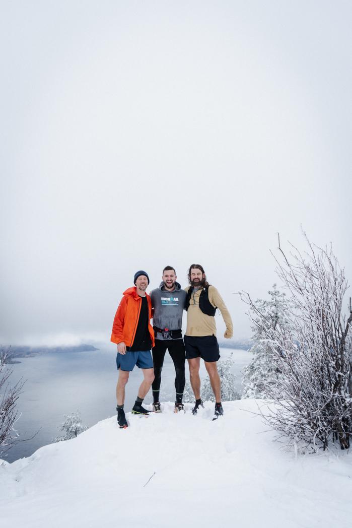 Three runners posing on a snowy ridge above Okanagan Lake during the Sweat Culture run club, trail running and sauna sessions in Peachland, BC