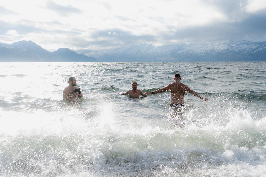 Three men fully submerged in the cold waves of Okanagan Lake in winter after a Sweat Culture sauna session, cold plunge in Peachland, BC